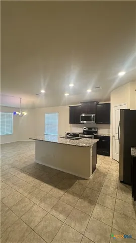 a large kitchen with stainless steel appliances kitchen island granite countertop a refrigerator a stove a sink and a microwave
