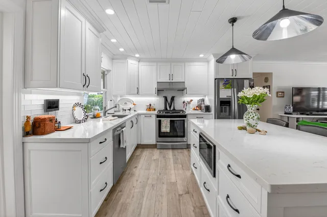 a kitchen with stainless steel appliances kitchen island granite countertop a white cabinets and wooden floor