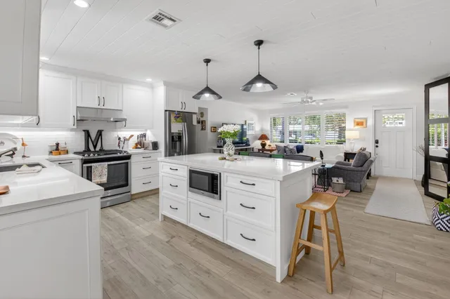 a kitchen with stainless steel appliances kitchen island granite countertop a sink a stove and a refrigerator