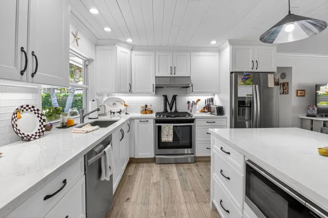 a kitchen with kitchen island white cabinets and refrigerator