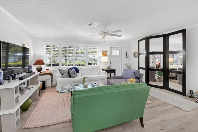 a living room with furniture large windows and flat screen tv
