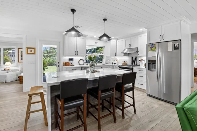 a kitchen with stainless steel appliances a dining table chairs stove and refrigerator