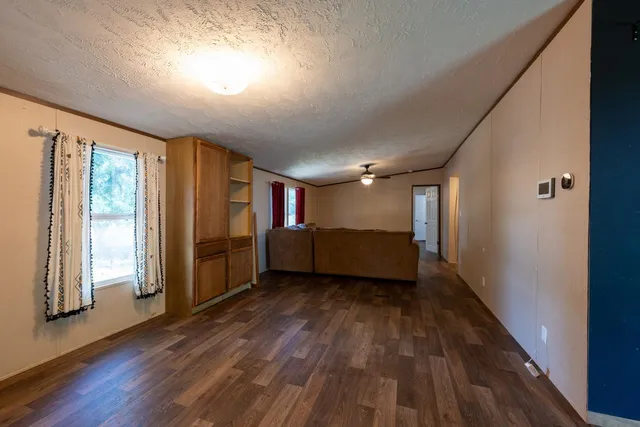 an empty room with wooden floor chandelier fan and windows