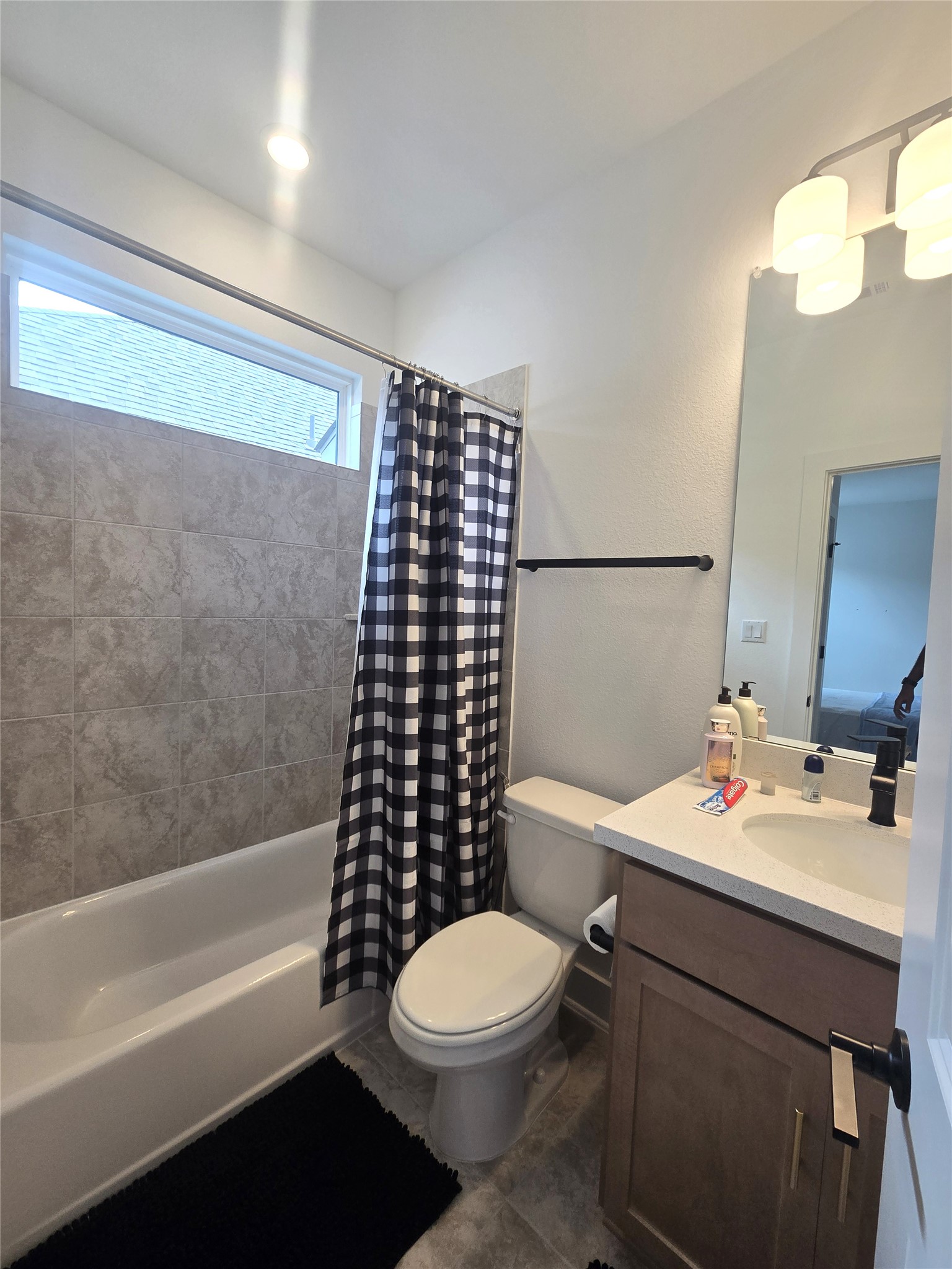124 Ribera Drive Liberty Hill, TX 78642 - Photo 18 of 40 A well-lit full bathroom features a combination tub and shower, a single vanity, and tiled flooring.