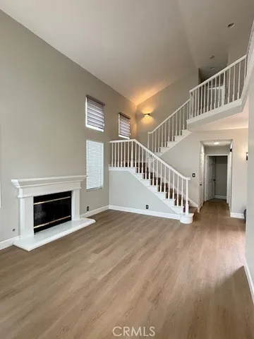 a view of an empty room with wooden floor fireplace and a window