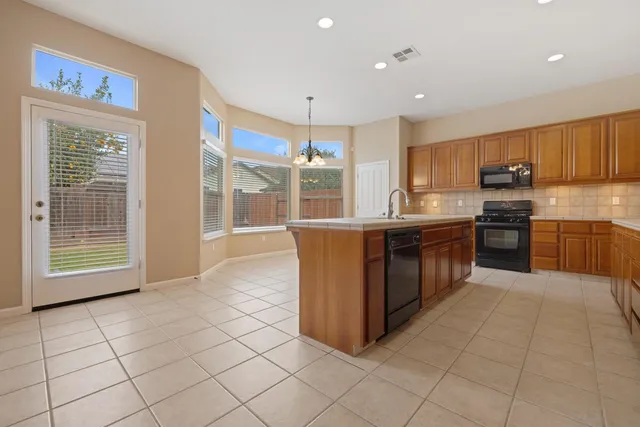 a kitchen with stainless steel appliances granite countertop a stove a sink and a microwave