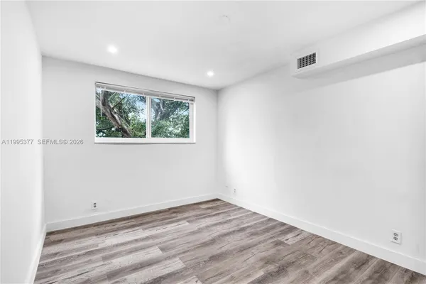 an empty room with wooden floor and window