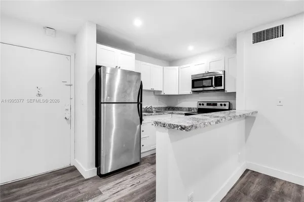 a kitchen with stainless steel appliances granite countertop a refrigerator a stove a microwave and a refrigerator