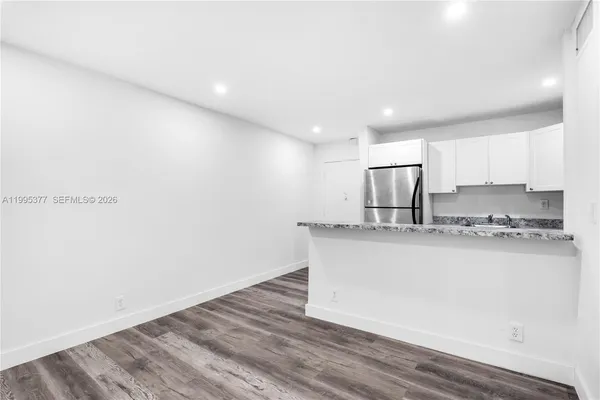 a kitchen with stainless steel appliances granite countertop a sink a stove a refrigerator with white cabinets and wooden floor