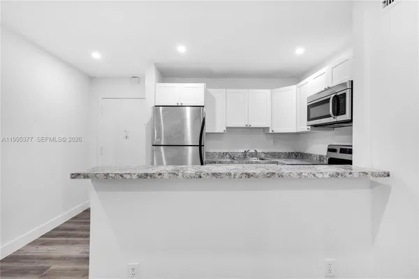 a kitchen with stainless steel appliances granite countertop a sink refrigerator and microwave