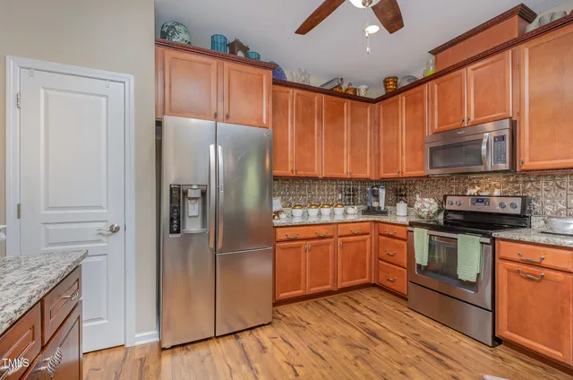 a kitchen with stainless steel appliances granite countertop a refrigerator a stove and a sink with cabinets