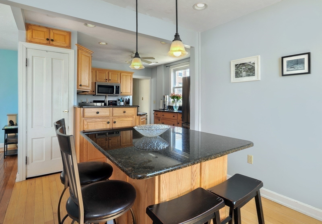 12 L Street Hull, MA 02045 - Photo 10 of 29 a kitchen with stainless steel appliances granite countertop a stove a refrigerator a kitchen island a sink dishwasher a dining table and chairs with wooden floor
