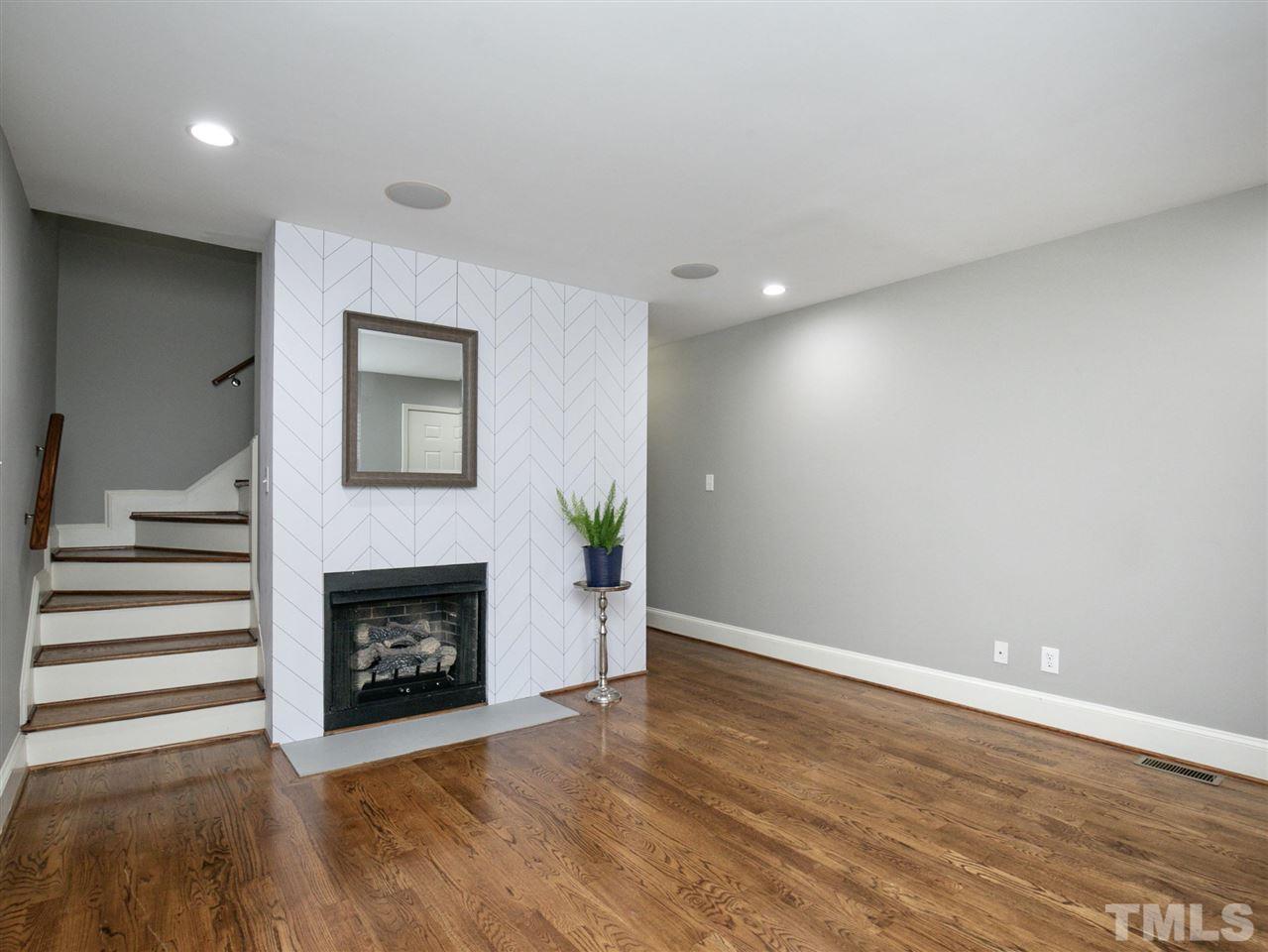 2542 Noble Road Raleigh, NC 27608 - Photo 5 of 27 a view of an empty room with wooden floor fireplace and a window