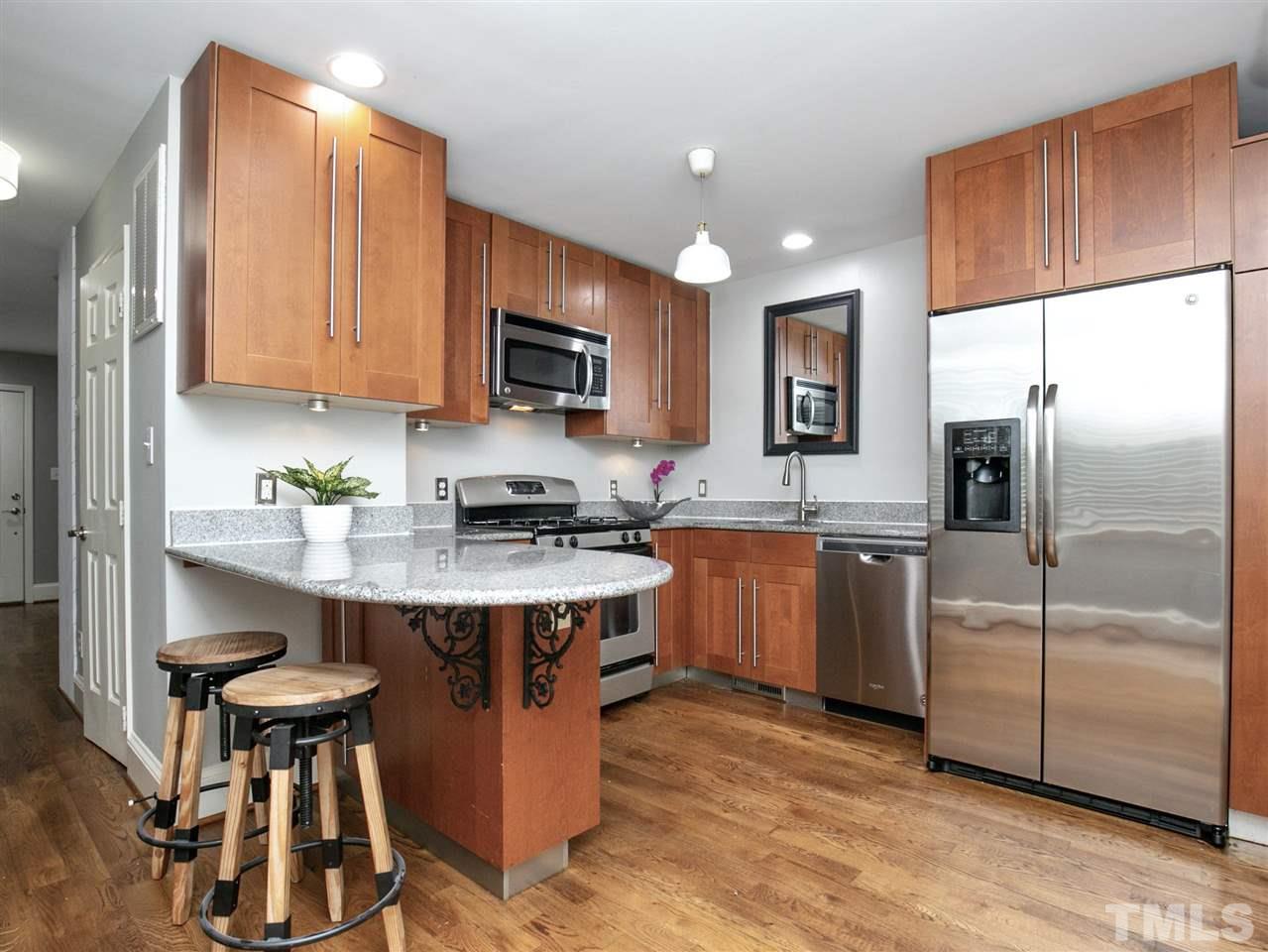 2542 Noble Road Raleigh, NC 27608 - Photo 9 of 27 a kitchen with stainless steel appliances granite countertop a stove a sink a microwave a refrigerator and white cabinets