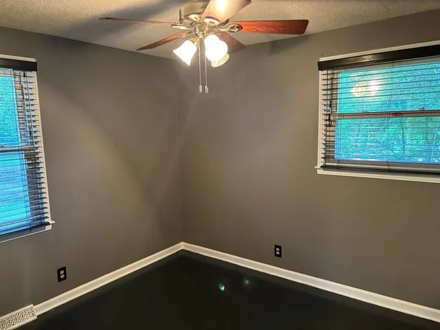 a view of an empty room with window and chandelier fan