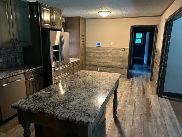 a kitchen with stainless steel appliances kitchen island granite countertop wooden cabinets and granite counter tops