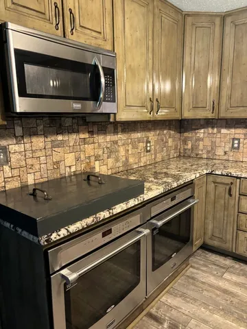 a kitchen with granite countertop stainless steel appliances a stove microwave and sink