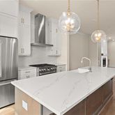 a kitchen with stainless steel appliances a chandelier a refrigerator a stove a sink dishwasher and white cabinets with wooden floor