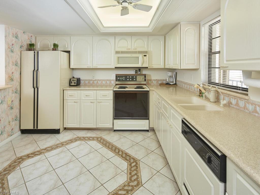 415 10th Avenue South, Unit 7 Naples, FL 34102 - Photo 6 of 15 a kitchen with a sink cabinets stainless steel appliances and a window
