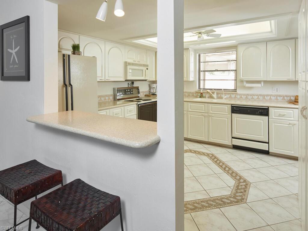 415 10th Avenue South, Unit 7 Naples, FL 34102 - Photo 7 of 15 a kitchen with granite countertop a sink cabinets stainless steel appliances and a window