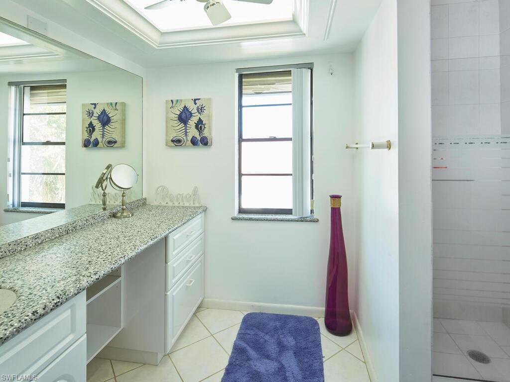 415 10th Avenue South, Unit 7 Naples, FL 34102 - Photo 9 of 15 a bathroom with a granite countertop sink a window and a mirror