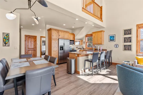 a dining room with stainless steel appliances kitchen island granite countertop a dining table chairs and a refrigerator