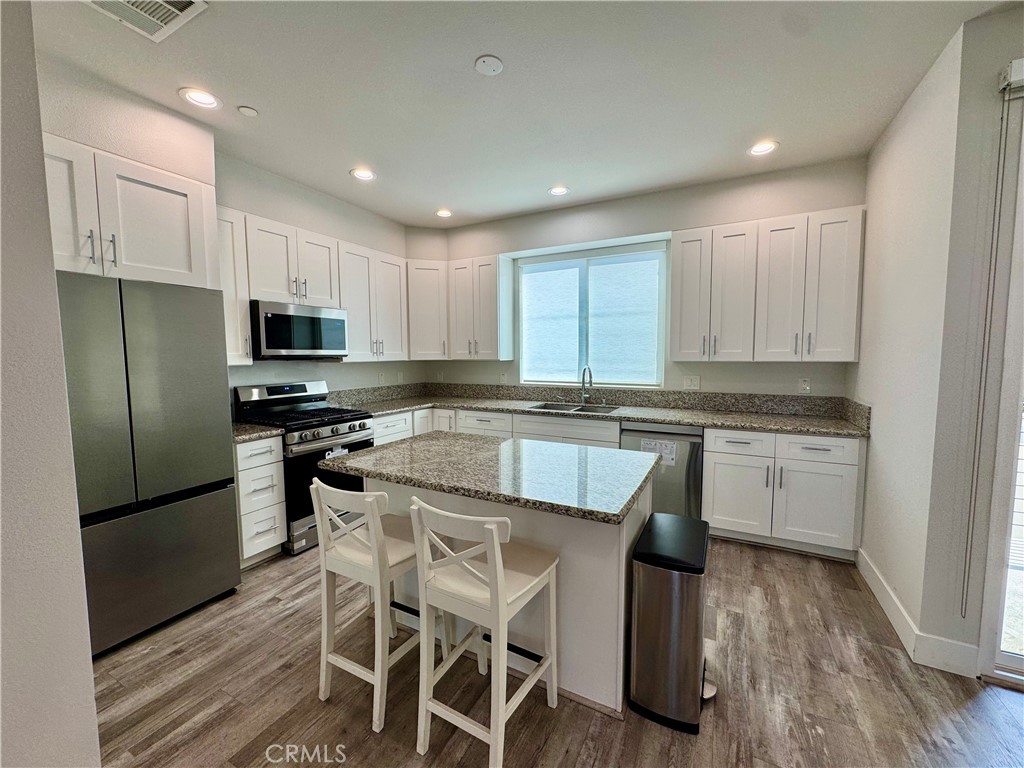 7958 Telegraph Road Downey, CA 90240 - Photo 4 of 38 a kitchen with kitchen island granite countertop white cabinets and stainless steel appliances