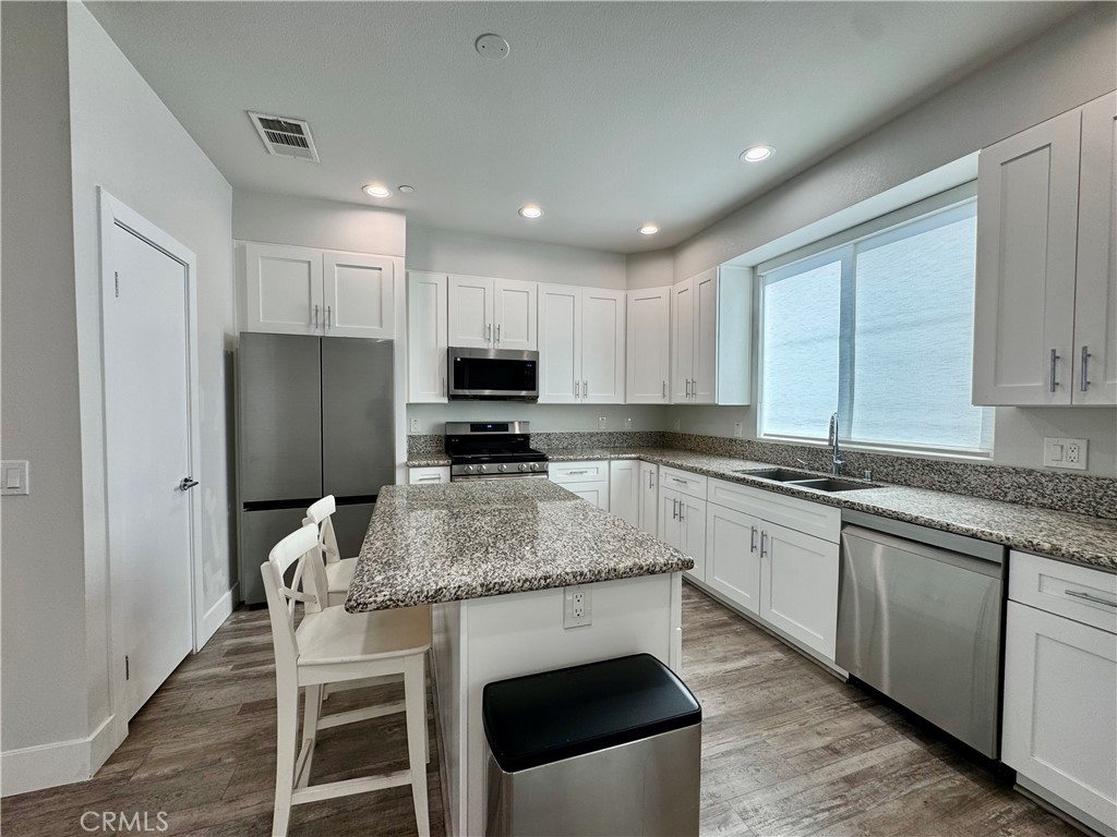 7958 Telegraph Road Downey, CA 90240 - Photo 5 of 38 a kitchen with stainless steel appliances granite countertop a stove a sink a microwave a refrigerator and cabinets