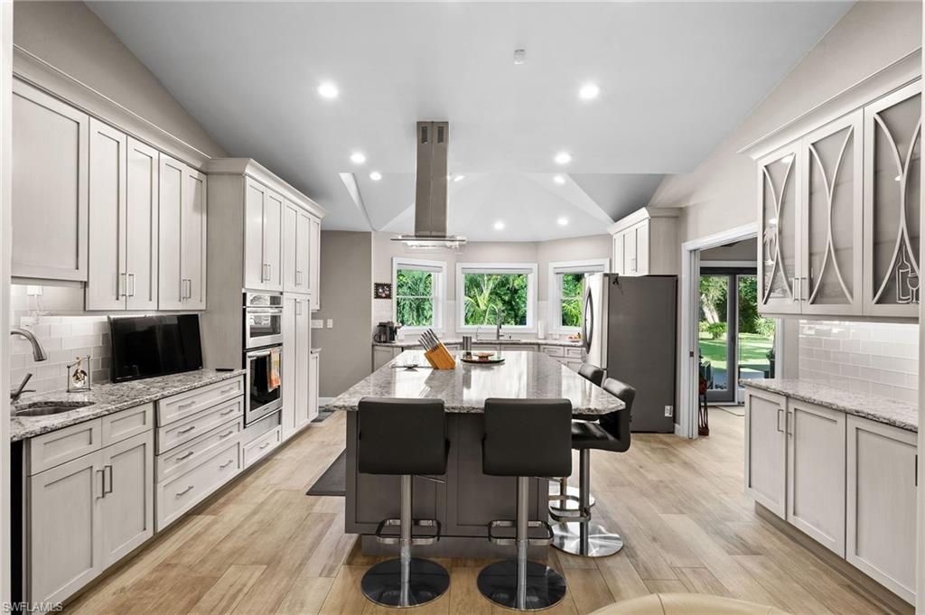 153 West Street Naples, FL 34108 - Photo 16 of 48 a kitchen with stainless steel appliances kitchen island granite countertop a refrigerator a stove top oven a sink dishwasher and white cabinets with wooden floor