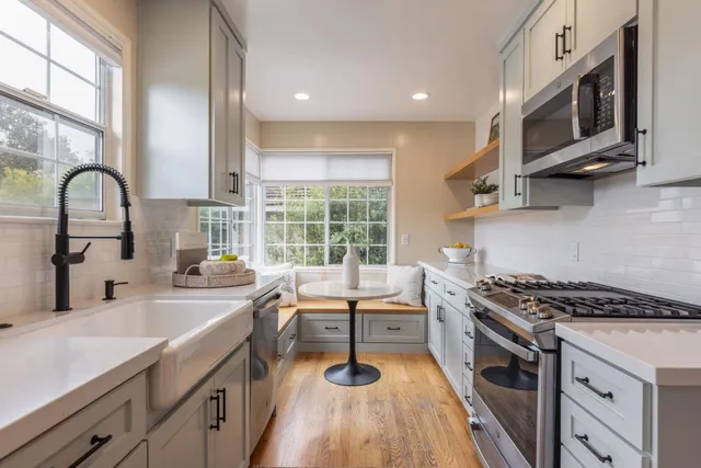 a kitchen with stainless steel appliances a sink a stove cabinets counter space and a window