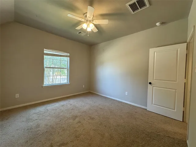 an empty room with a chandelier fan and windows