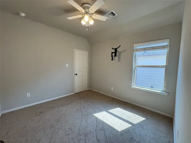 an empty room with a window and a fan
