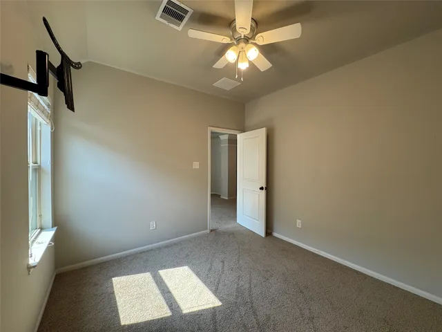a view of an empty room with a chandelier fan