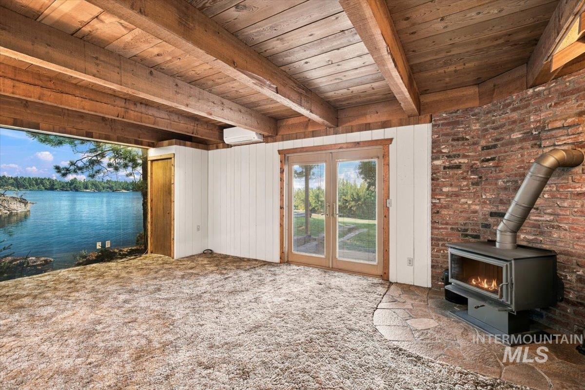 10201 Willis Road Middleton, ID 83644 - Photo 21 of 38 Wood-beamed ceiling, exposed brick wall, and a wood-burning stove with a stone-finish hearth