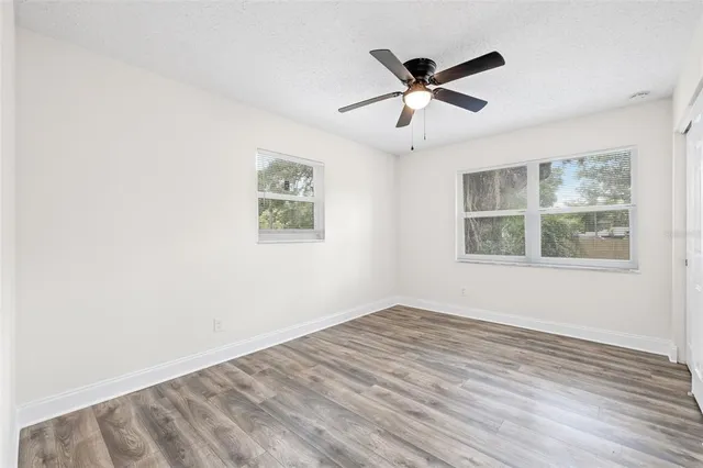 a view of empty room with wooden floor and ceiling fan