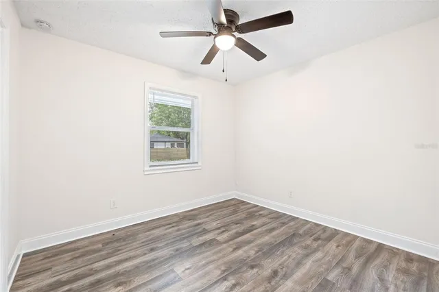an empty room with a window and a ceiling fan