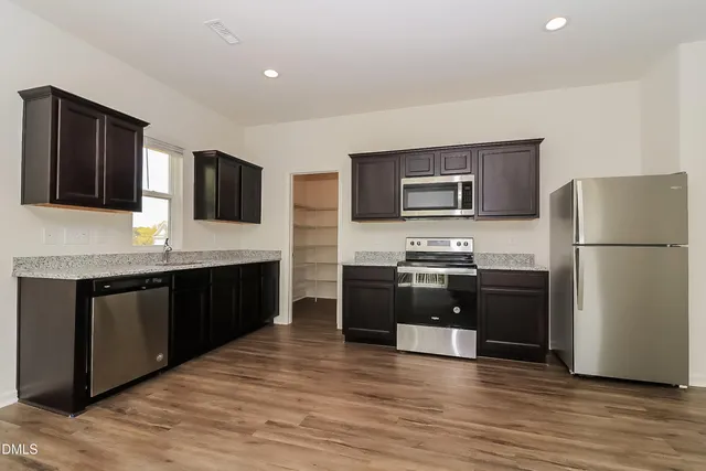 a kitchen with stainless steel appliances granite countertop a refrigerator and a stove top oven