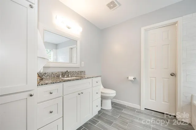 a bathroom with a granite countertop sink a toilet and a mirror