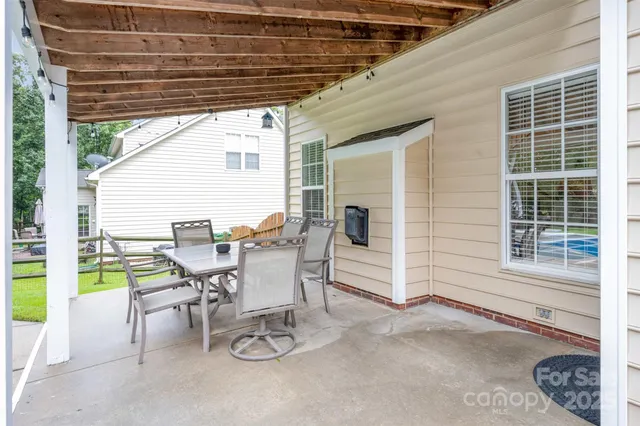 a patio with a table and chairs and potted plants