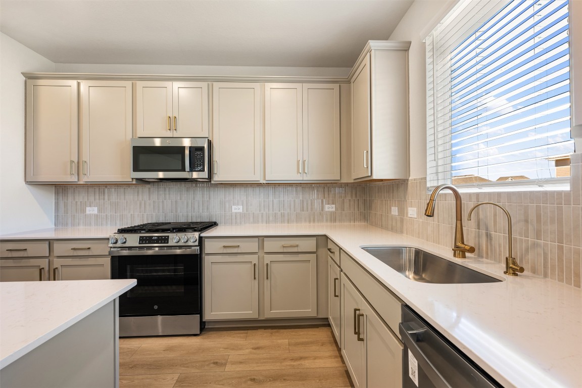 135 Silverleaf Spur Bastrop, TX 78602 - Photo 18 of 40 a kitchen with stainless steel appliances granite countertop white cabinets sink and window