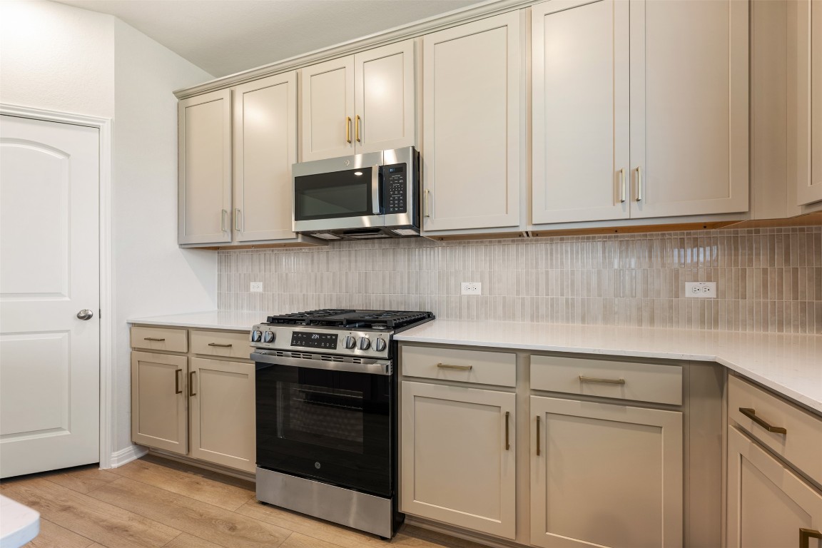 135 Silverleaf Spur Bastrop, TX 78602 - Photo 19 of 40 a kitchen with white cabinets and a stove