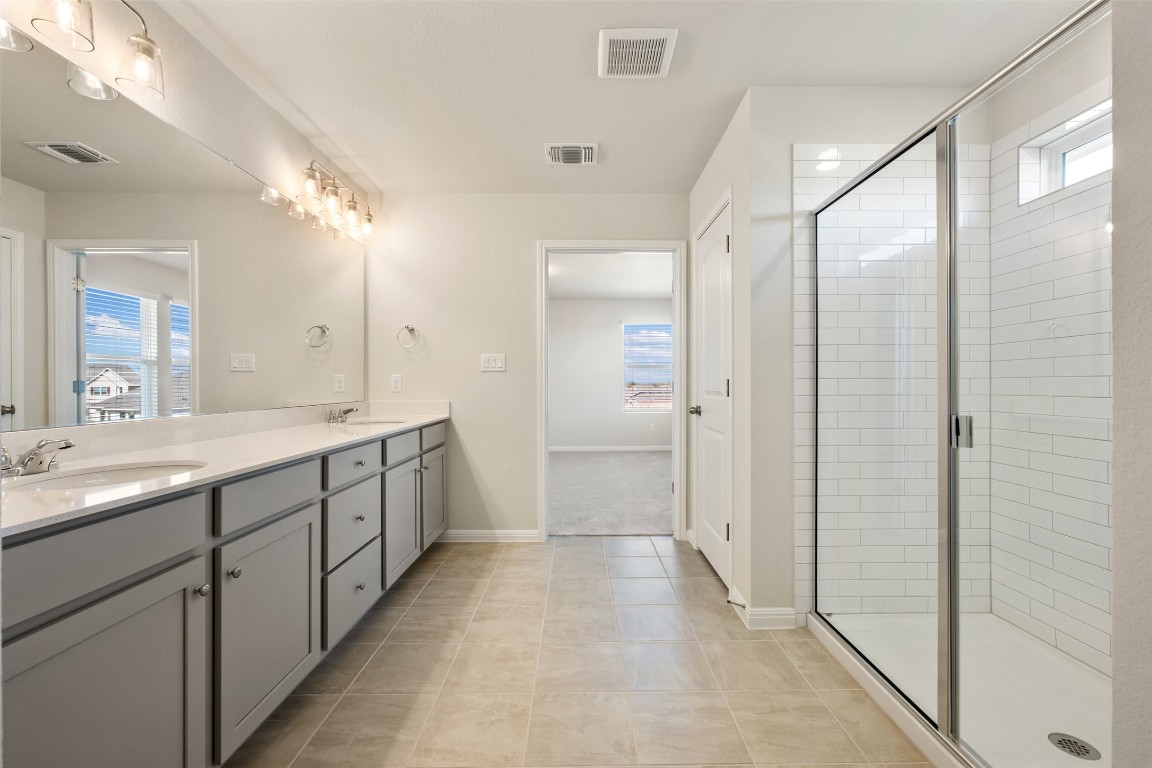 135 Silverleaf Spur Bastrop, TX 78602 - Photo 33 of 40 a bathroom with a double vanity sink and mirror with shower