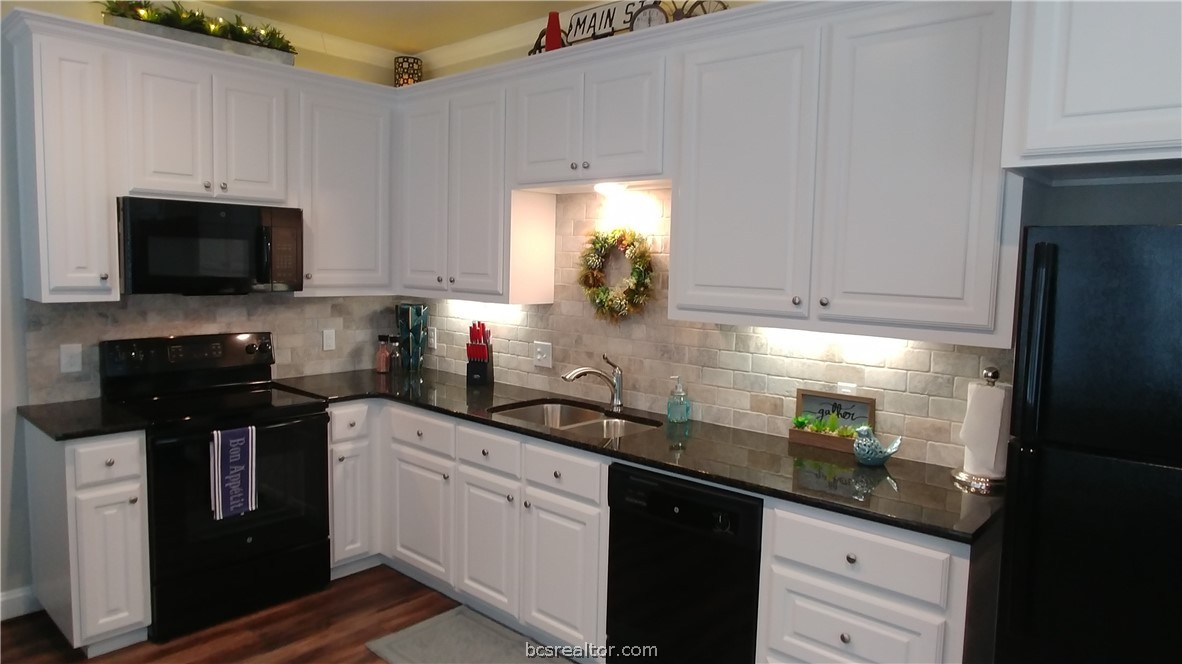 401 North Main Street, Unit 306 Bryan, TX 77803 - Photo 9 of 11 a kitchen with granite countertop white cabinets and black appliances