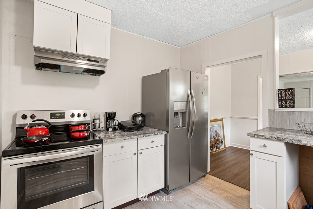 7838 South Langston Road Seattle, WA 98178 - Photo 22 of 27 a kitchen with stainless steel appliances granite countertop a stove sink and refrigerator