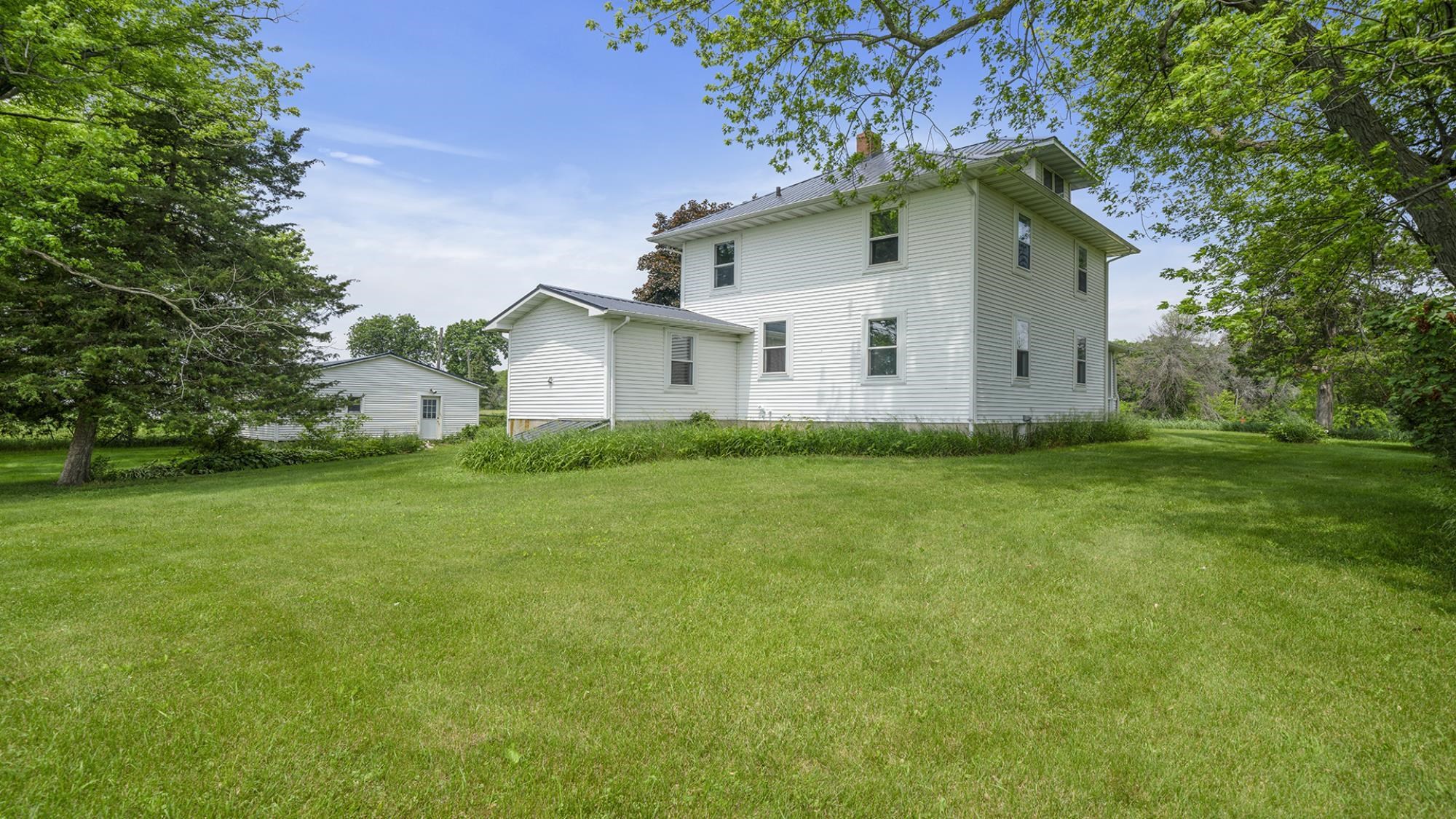 4407 East River Road Ridott, IL 61067 - Photo 10 of 45 a white house that has a tree in front of it