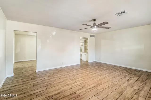 a view of an empty room with window and a ceiling fan