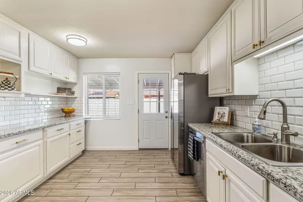 a kitchen with granite countertop a refrigerator and a sink