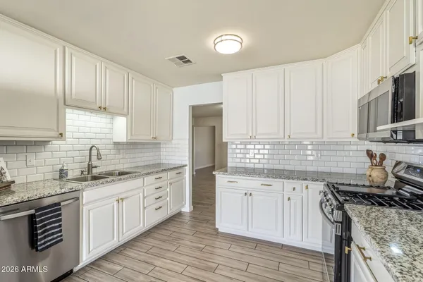 a kitchen with stainless steel appliances granite countertop a stove sink and cabinets