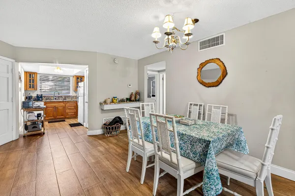 a dining room with furniture a chandelier and wooden floor