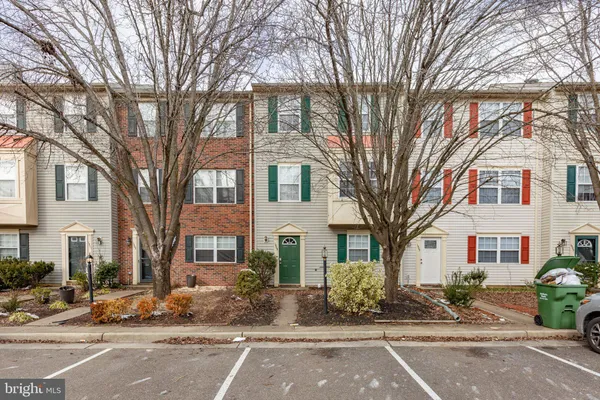 a front view of a building with trees and cars